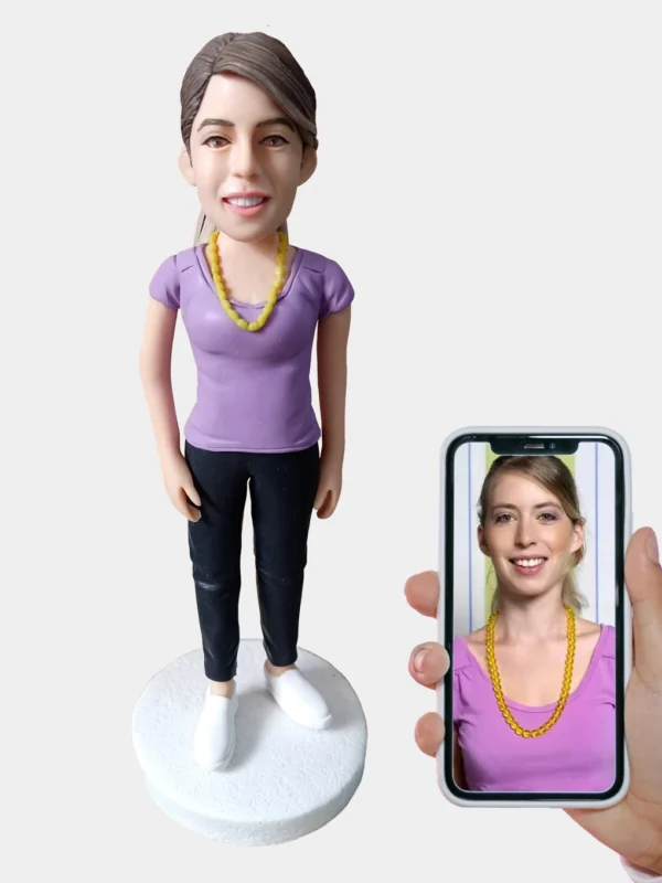 Custom clay figurine made from a woman's photo displayed on a smartphone. Personalized handcrafted sculpture gift.